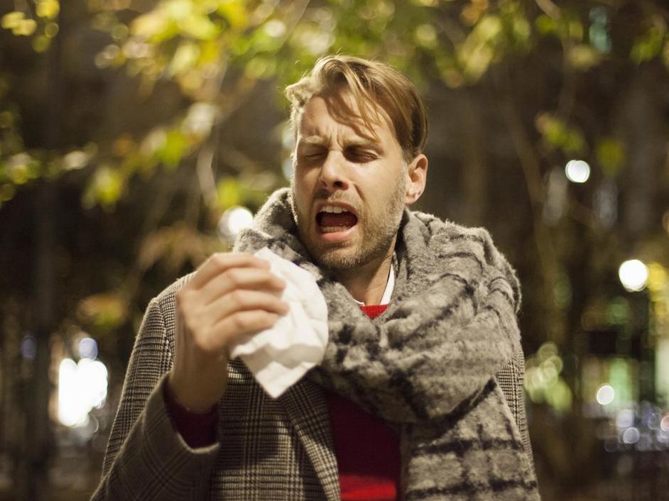 Tröpfcheninfektion: Mann niest in ein Taschentuch und verteilt Bakterien oder Viren