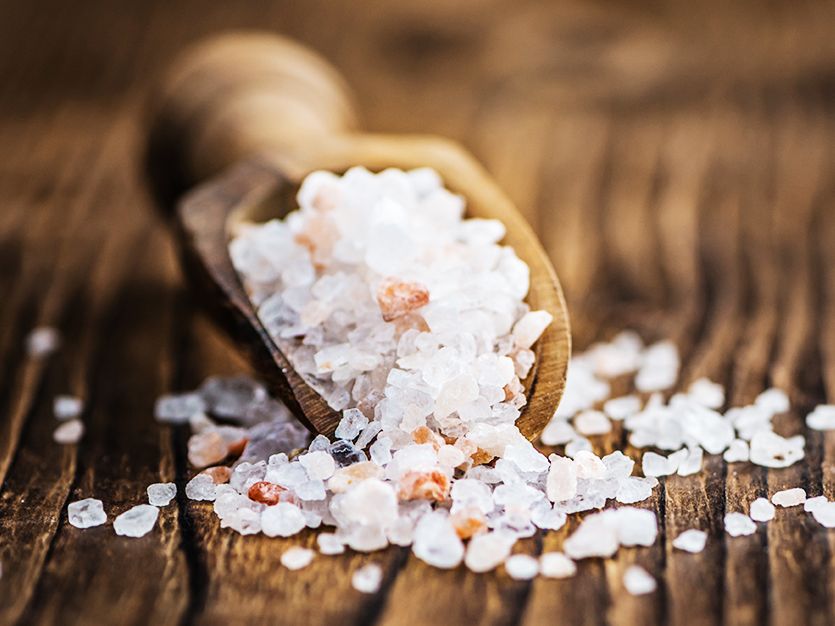 Schaufel mit grobem Salz auf Holztisch