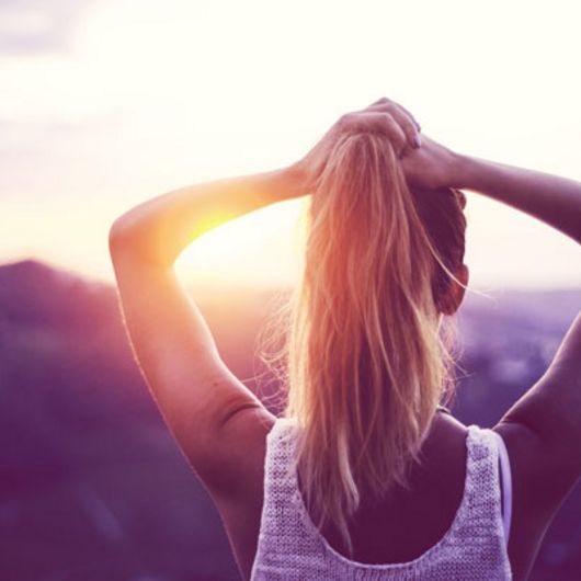 Frau genießt unbeschwert den Sonnenuntergang, frei von PMS Beschwerden