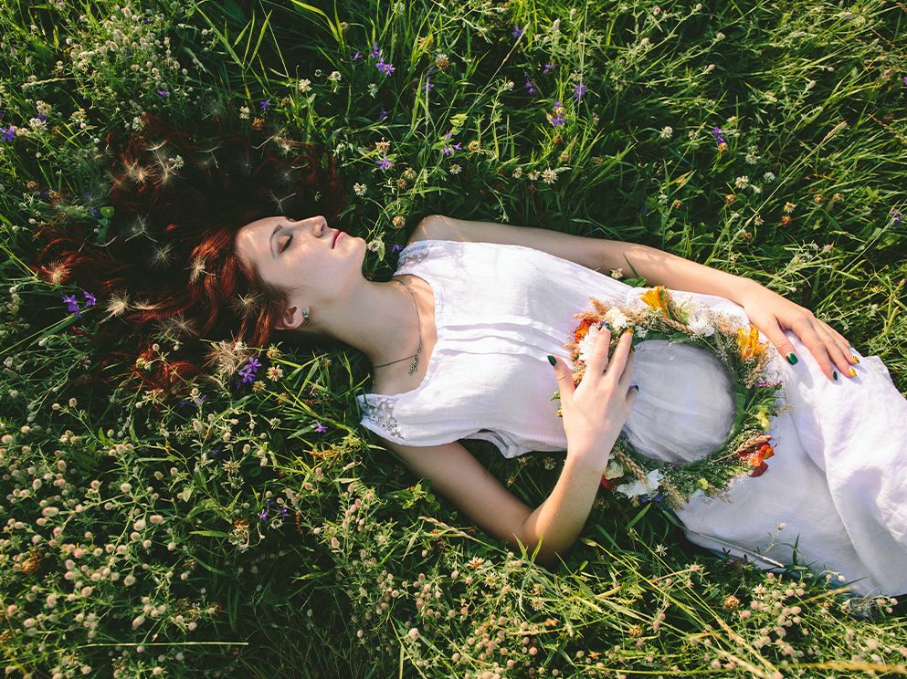 Frau liegt entspannt auf Wiese - Pflanzliche Schlaf-und Beruhigungsmittel
