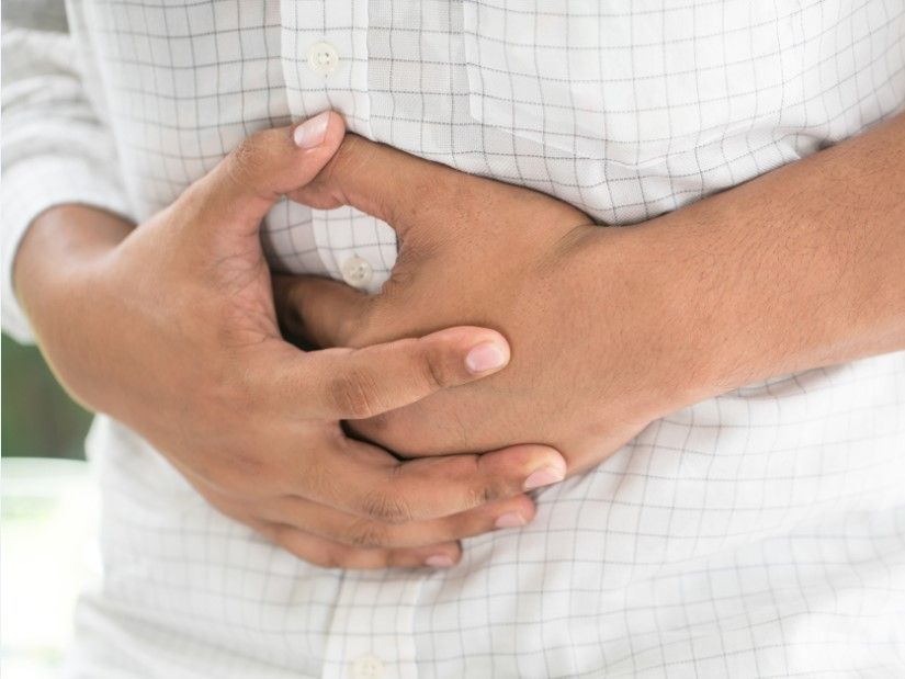 Mann hält sich den Bauch, weil er Magen-Darm-Beschwerden hat