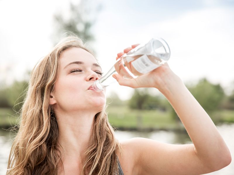 Frau trinkt Wasser gegen Verdauungsbeschwerden